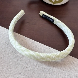 Detail of light green plaid fabric headband with black Handmade woven label on the inner side
