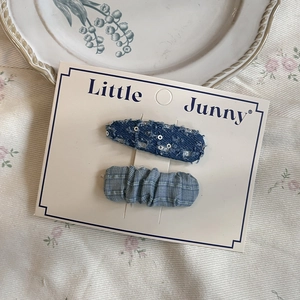 Close-up of blue denim and checkered heart hair clips on white display card