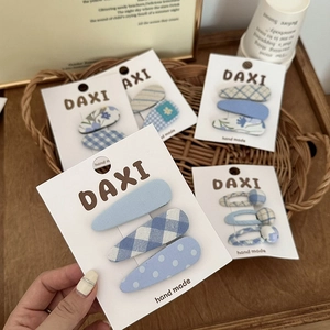 Detail shot of blue gingham and floral fabric hair clips on a white display card