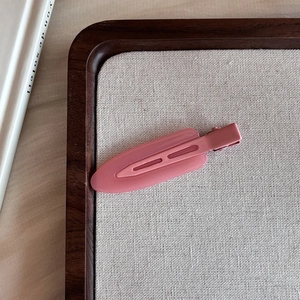 Close-up of pink seamless candy-colored hair clip on a wooden tray with linen