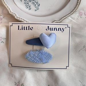 Close-up of blue plaid heart clip and tweed bow hair pins on a decorative display card