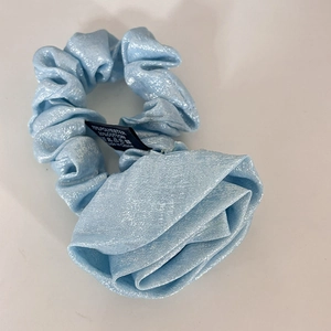 Detail of light blue rose fabric scrunchie showing 70% polyester and 30% cotton label