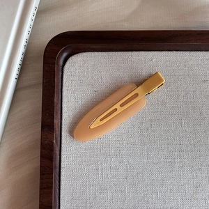 Close-up of amber matte seamless hair clip with resin texture on a wooden tray