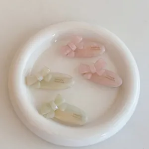 Pink and cream acetate bow hair clips set with marbled texture in a white tray