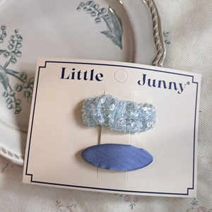 Blue glitter wavy hair clip and purple fabric barrette set on branded display card