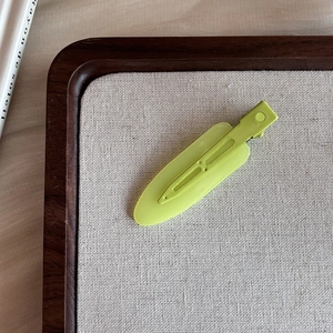 Detailed macro view of matte avocado green seamless hair clip on a minimalist display