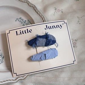 Blue denim fabric hair clips with heart pattern and fringe detail on display card