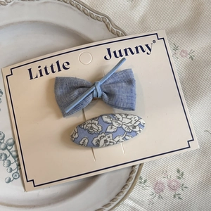Blue plaid bow and floral fabric hair clips displayed on an elegant ceramic plate