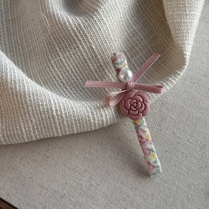 Floral camellia hair clip with pink ribbon bow and pearl detail on textured linen fabric