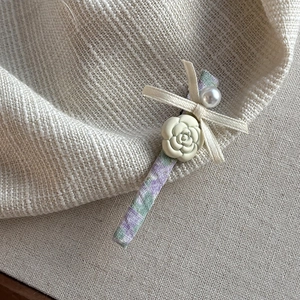Floral camellia hair clip with white ribbon bow and pearl detail on fabric headband