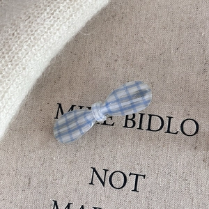 Elegant blue plaid bow hair clip in translucent resin with fine glitter on linen cloth