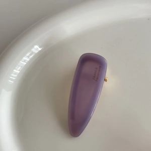 Close-up of purple acetate hair clip with gold metal part and handmade engraving