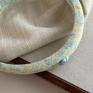 Macro shot of camellia floral headband with blue fabric texture and metal buckle detail