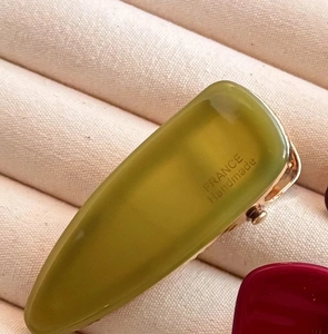Detailed close-up of an olive green acetate hair clip with gold France Handmade lettering
