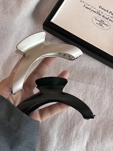 Détails des pinces à cheveux en métal argent mat et noir brillant sur fond de tissu