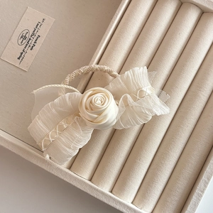 Elegant cream white fabric rose hair tie with pleated mesh wings on display tray