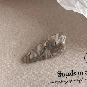 Detailed macro view of acetate hair clip with grey marble pattern and engraved handmade text