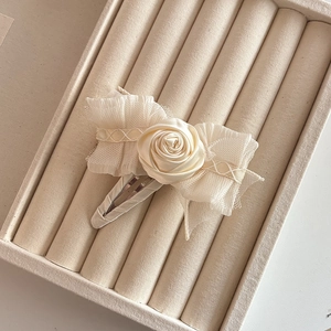 Close-up of elegant cream fabric rose hair clip with delicate mesh and lace detailing