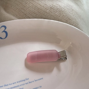 Detail of pink matte rectangular hair clip on a white ceramic plate with metal crocodile clip