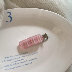 Pink and white checkered acetate hair clip with silver metal alligator base on ceramic