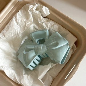 Detailed view of large cream blue bow hair claw clip resting in gift box packaging