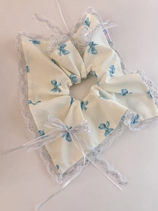 Détail du bavoir en dentelle pour animaux avec motifs de nœuds bleus et étiquette Hand made