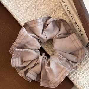 Chouchou en satin rose champagne avec coutures apparentes sur fond en maille