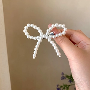 Dettaglio del fermaglio per capelli a fiocco con perle fatte a mano e clip in metallo