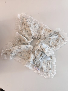 Détail d'un chouchou à carreaux bleus avec bordure en dentelle et nœud fait à la main