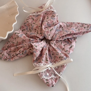 Détail d'un chouchou floral avec bordure en dentelle et nœuds en soie crème sur fond blanc
