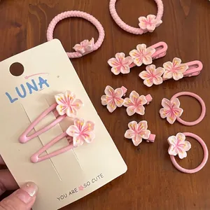 Set de pinces à cheveux fleur de cerisier rose avec élastiques sur surface en bois
