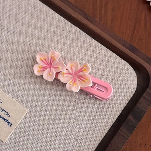 Gros plan de barrettes à cheveux fleurs de cerisier roses sur fond en toile texturée