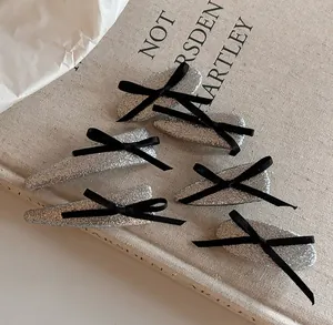 Detail view of 6-piece silver glitter hair clip set with black ribbon bows on book
