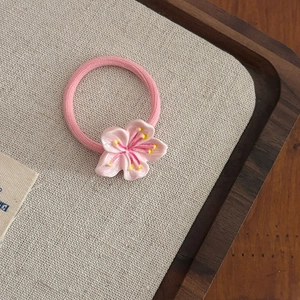 Détail d'un élastique à cheveux fleur de cerisier rose avec pétales en résine douce