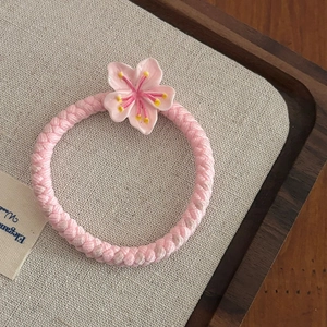 Détail d'un élastique à cheveux cerisier rose sur un plateau en bois et fond en toile