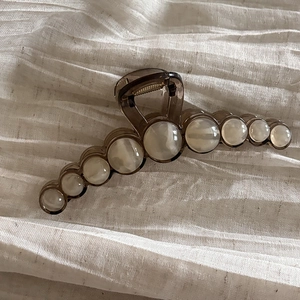 Detail of a large brown acrylic hair claw clip featuring gradient pearlescent beads