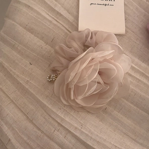 Détail d'un chouchou floral champagne avec pétales en gaze et pendentif en perles
