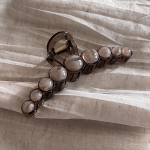 Elegant dark brown translucent acrylic hair claw clip with cream pearls on beige fabric