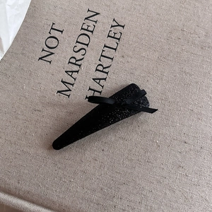 Sparkly black triangle hair clip with elegant satin ribbon bow on linen background