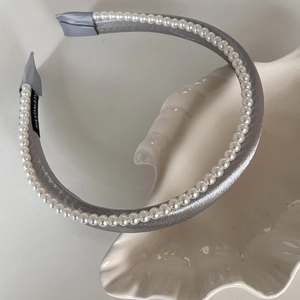 Détail d'un serre-tête en velours gris argenté avec perles blanches et étiquette fait main