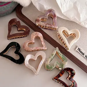 Eight-piece set of heart-shaped acetate hair claws in various colors on a wooden tray