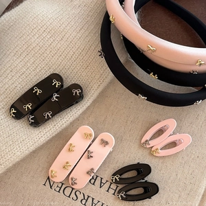 Accessori per capelli rosa e neri con fiocchi d'argento su sfondo di tessuto