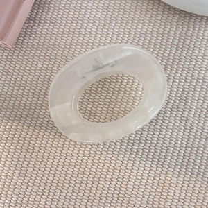 Gros plan sur une pince à cheveux en résine beige crème au design ovale évidé