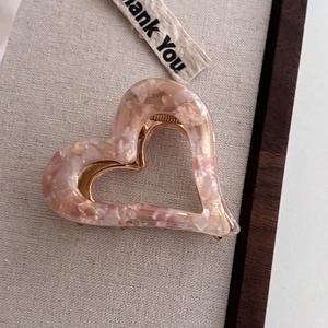 Detail of pink marble acetate heart hair claw clip with golden metal inner teeth mechanism