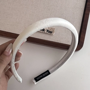 Détail d'un serre-tête blanc vintage en tissu avec étiquette faite main et texture