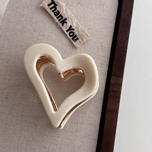 Detailed macro view of heart-shaped cream acetate hair claw clip with golden metal accents