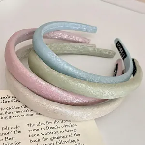 Cerchietti imbottiti in raso celeste, rosa, verde e beige su un libro aperto