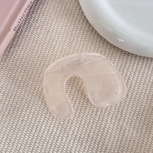 Gros plan d'une pince à cheveux rose en forme de U avec texture gelée sur un tapis