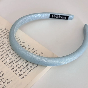 Dettaglio di un cerchietto imbottito azzurro in tessuto luccicante su sfondo di un libro