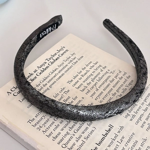 Dettaglio ravvicinato della trama scintillante di un cerchietto sottile su un libro aperto